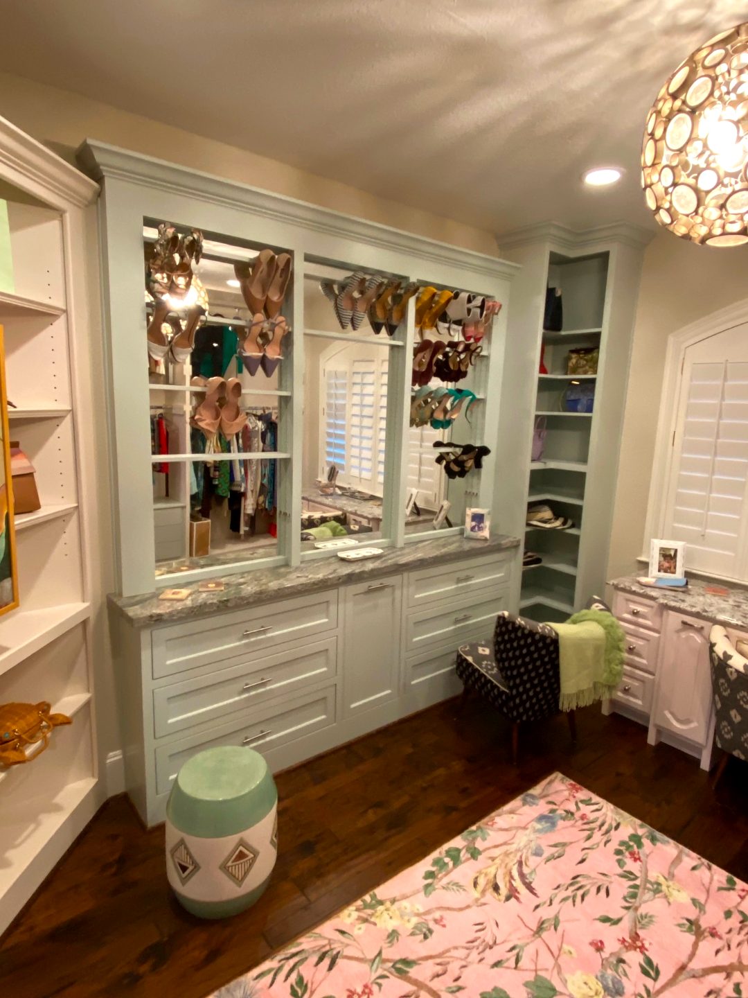 Custom walk-in closet system with shoe display shelving, drawer banks and granite-topped vanity