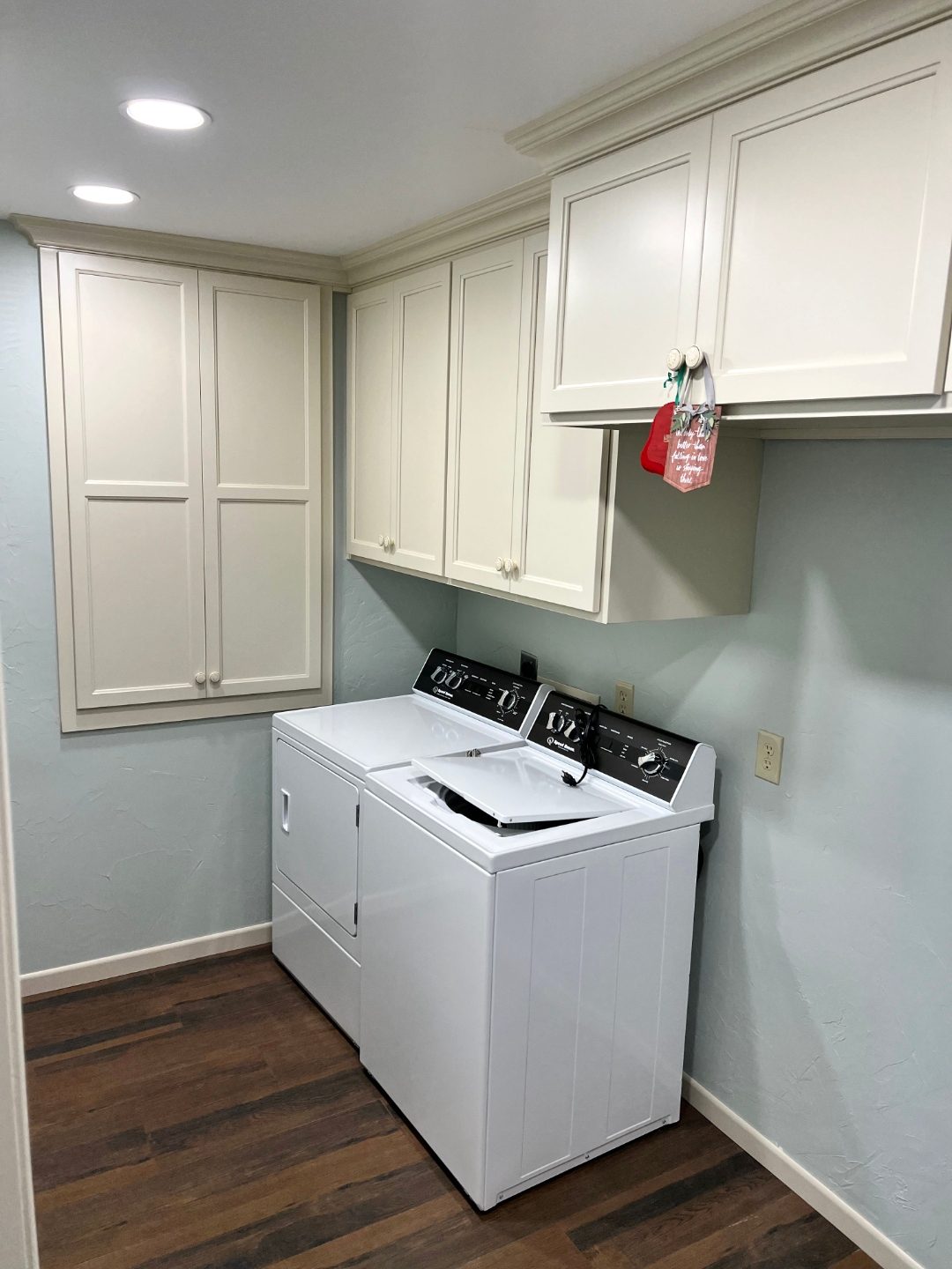 Custom laundry room cabinets with white uppers over washer and dryer